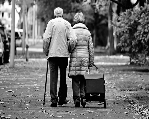Older man walking in a city park during autumn