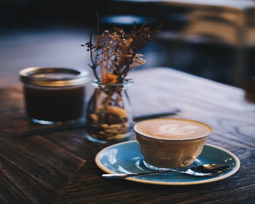 Glass of water next to a morning coffee on a wooden table