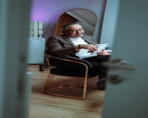 Middle aged man reading a book in a comfortable armchair at home